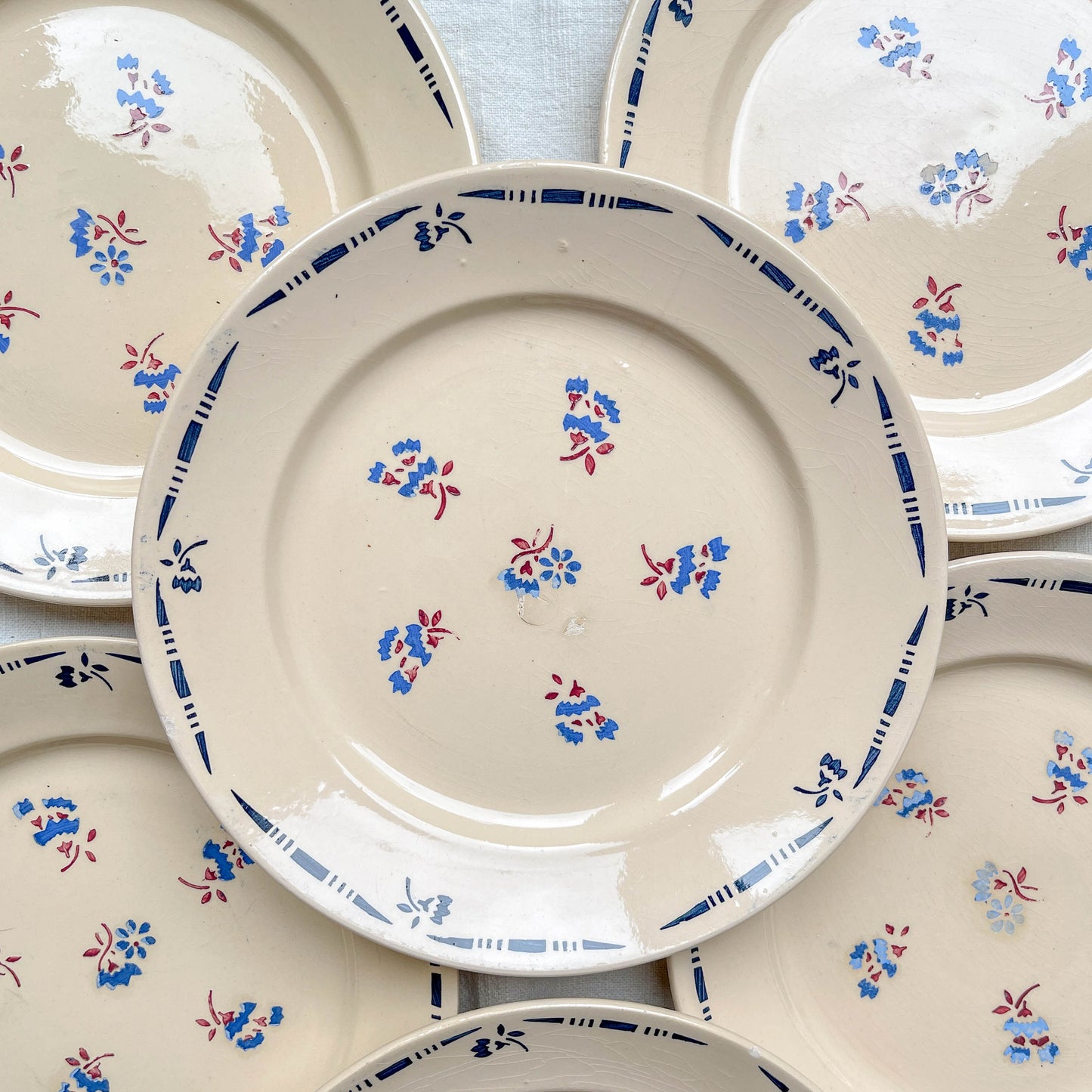 Lot de 8 assiettes plates en porcelaine vintage K&G Lunéville, modèle "Flore" des années 1950, décorées de petites fleurs bleues délicates.