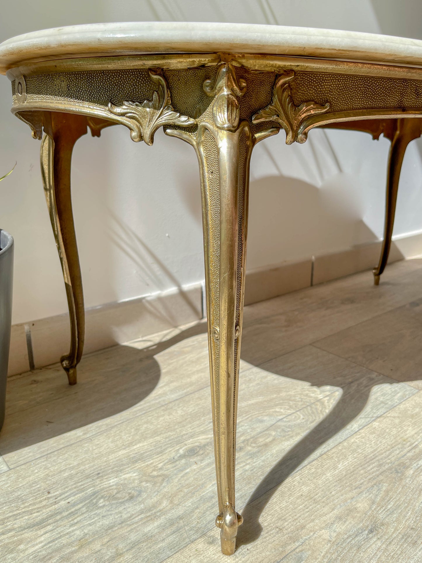 Table basse vintage ovale avec plateau en marbre blanc et pieds en bronze patiné, style chic et rétro pour salon.