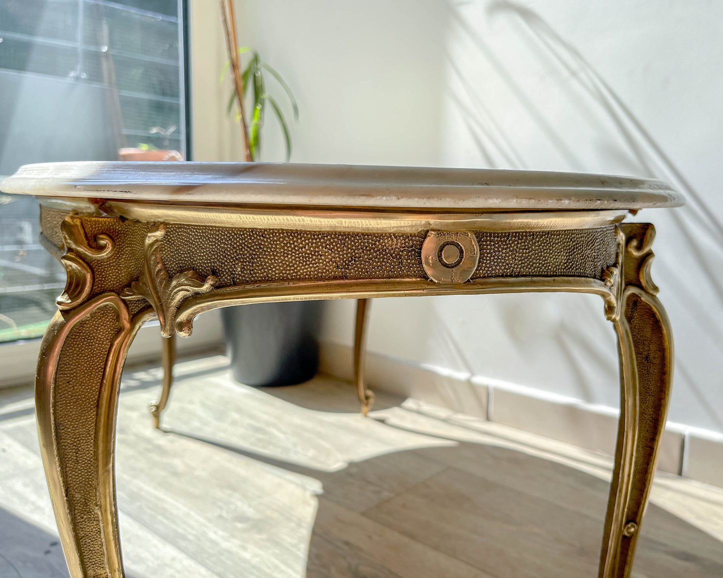 Table basse vintage ovale avec plateau en marbre blanc et pieds en bronze patiné, style chic et rétro pour salon.