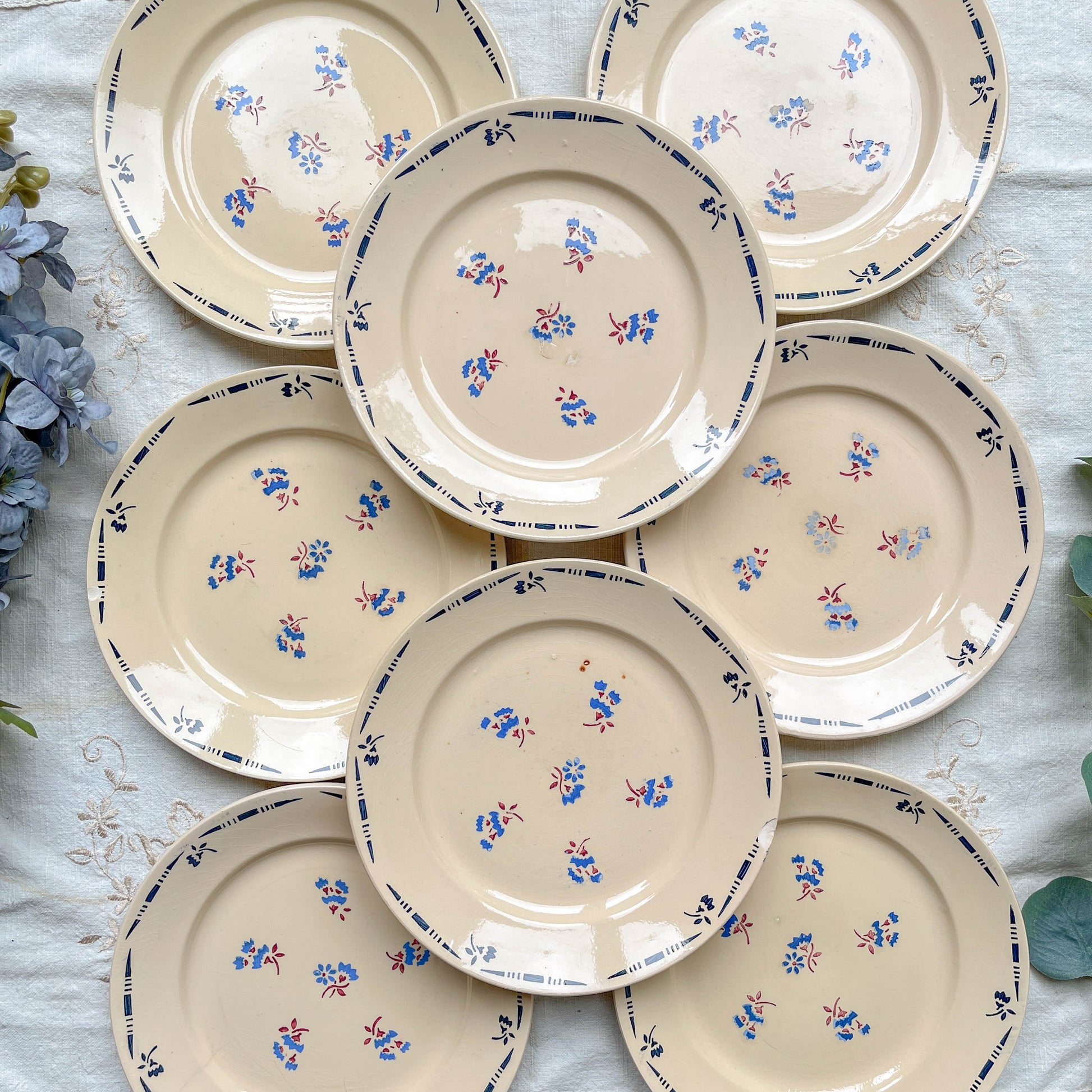 Lot de 8 assiettes plates en porcelaine vintage K&G Lunéville, modèle "Flore" des années 1950, décorées de petites fleurs bleues délicates.