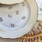 Assiettes vintage en porcelaine blanche ornées d’un motif floral doré et d’une bordure jaune pastel – Fabrication L'Amandinoise, années 1950