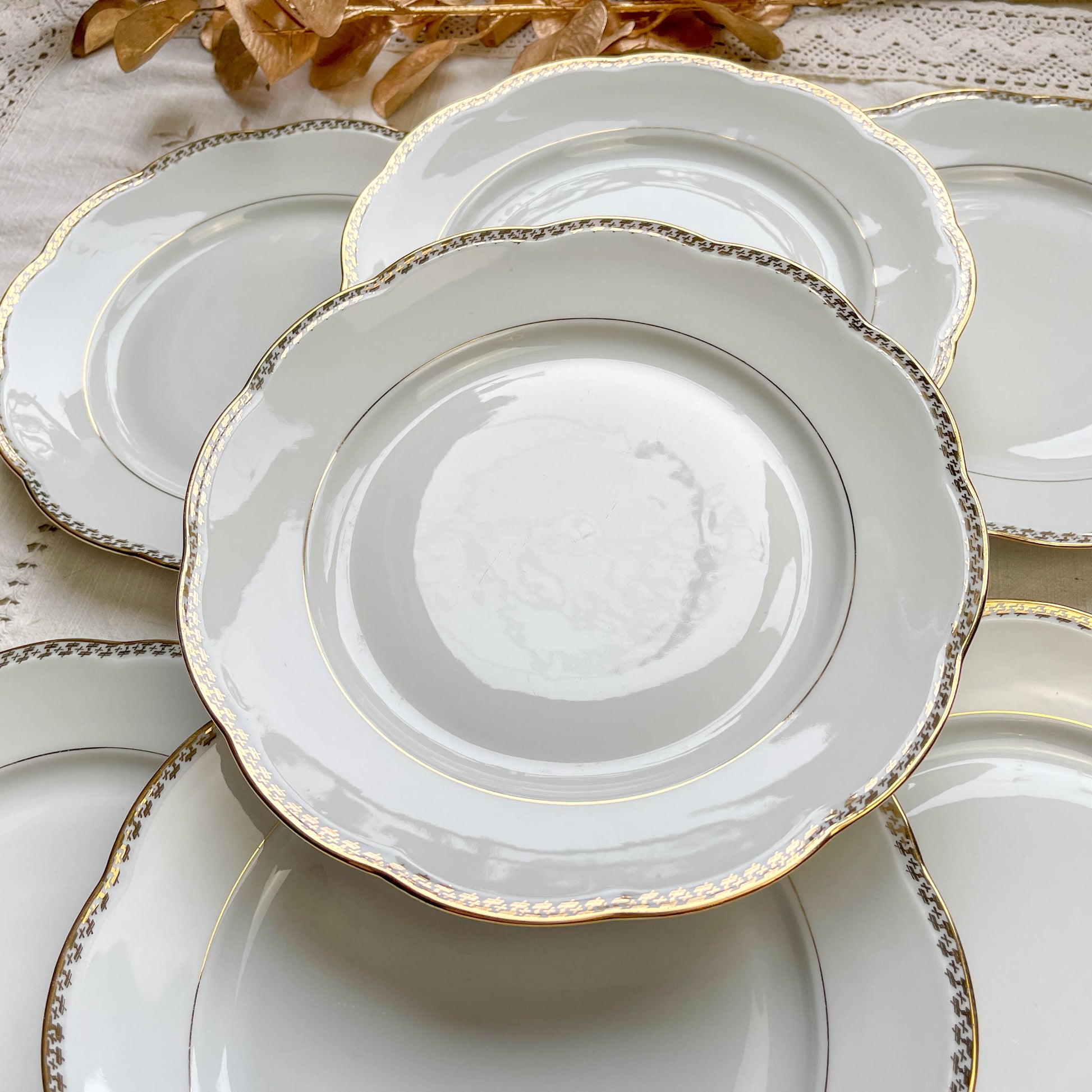 Ensemble de 7 assiettes plates vintage en porcelaine blanche avec décor doré géométrique SPF, vaisselle ancienne élégante pour table rétro ou collection.