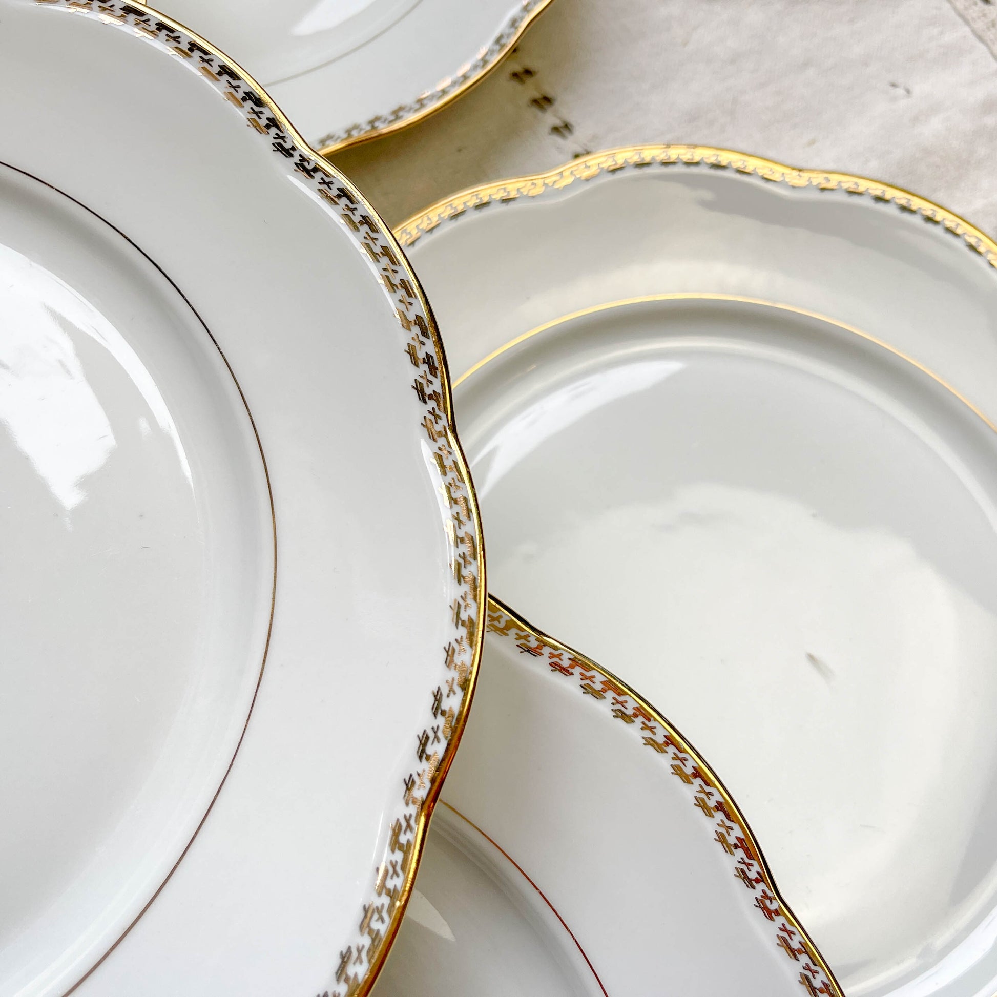 Ensemble de 7 assiettes plates vintage en porcelaine blanche avec décor doré géométrique SPF, vaisselle ancienne élégante pour table rétro ou collection.