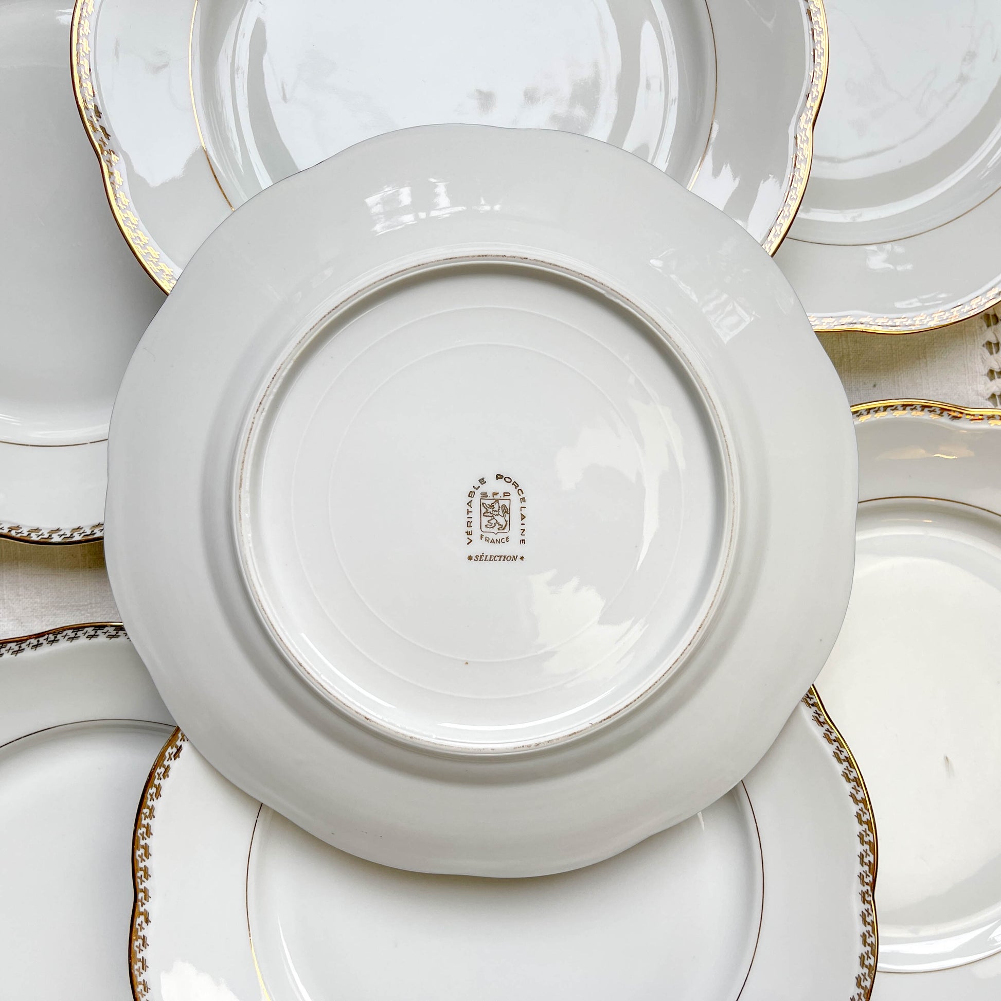 Ensemble de 7 assiettes plates vintage en porcelaine blanche avec décor doré géométrique SPF, vaisselle ancienne élégante pour table rétro ou collection.