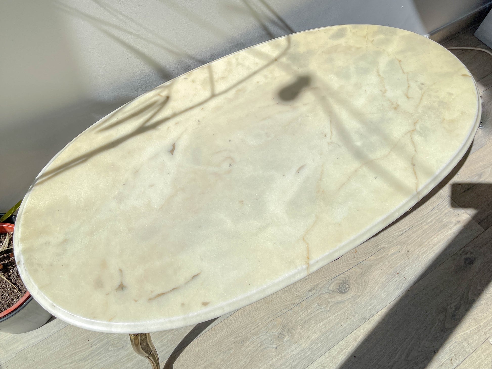 Table basse vintage ovale avec plateau en marbre blanc et pieds en bronze patiné, style chic et rétro pour salon.