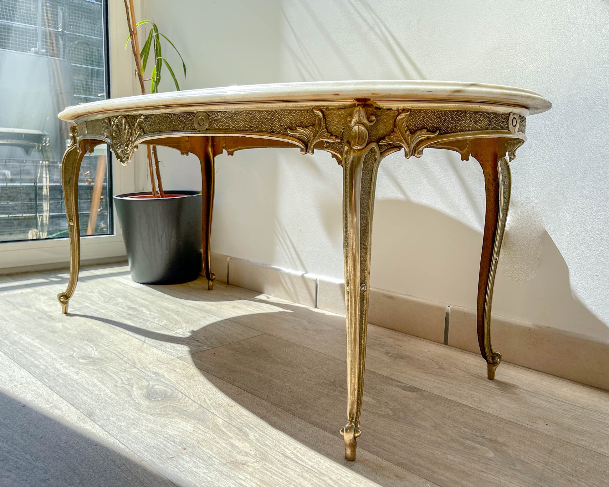 Table basse vintage ovale avec plateau en marbre blanc et pieds en bronze patiné, style chic et rétro pour salon.