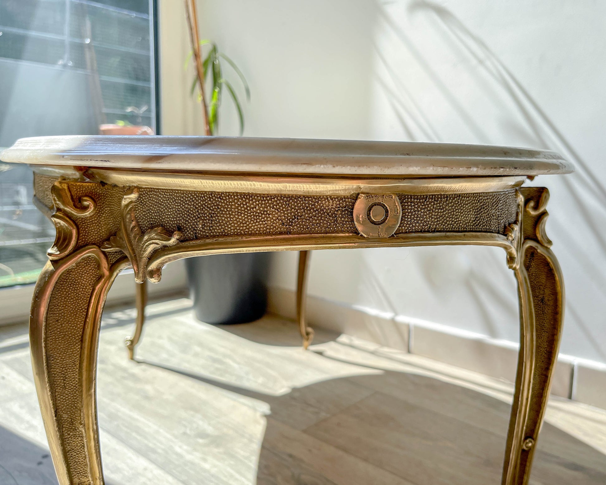 Table basse vintage ovale avec plateau en marbre blanc et pieds en bronze patiné, style chic et rétro pour salon.