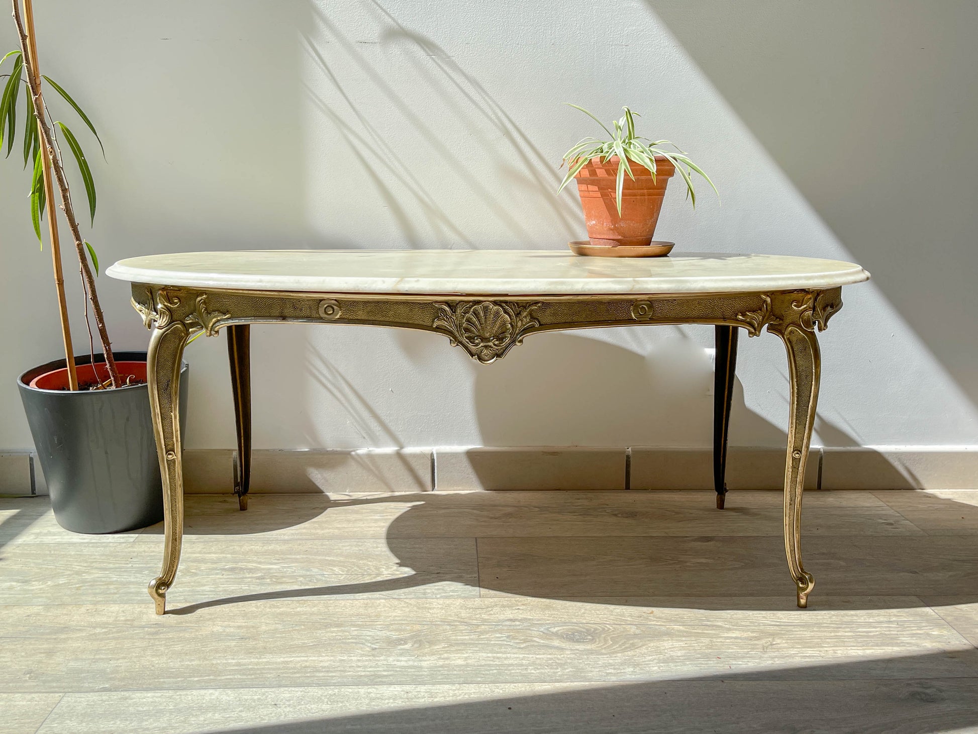 Table basse vintage ovale avec plateau en marbre blanc et pieds en bronze patiné, style chic et rétro pour salon.